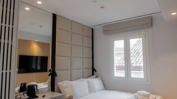 A modern hotel room with a bed, a desk, and a chair.