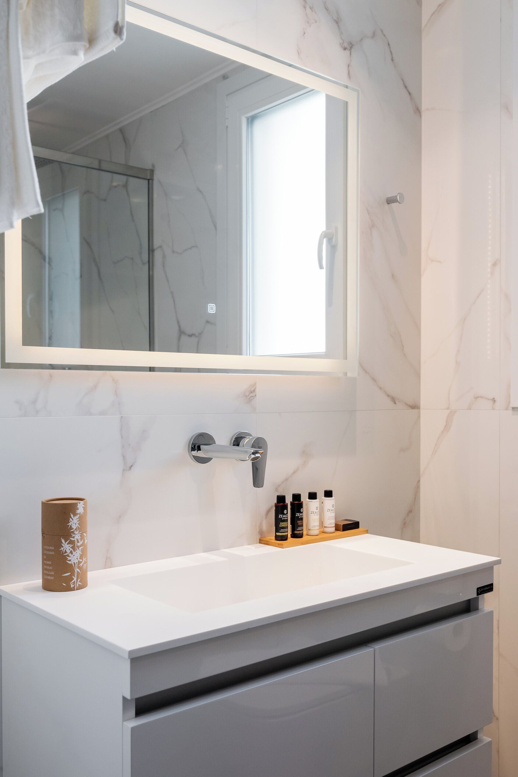 A bathroom with a white marble sink, a mirror, and a shower enclosure.