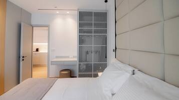 A modern bedroom with a large bed, a bedside table, a wardrobe, and a built-in bench.