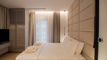 A modern bedroom with a large bed, a TV, and a wardrobe.