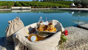 Escena junto a la piscina con una mesa que sostiene un postre, una botella y una rosa.