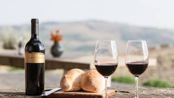 A bottle of wine, two glasses of red wine, and a loaf of bread on a wooden table with a rustic background.