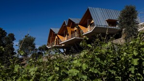 Una casa moderna con varios niveles y balcones, rodeada de vegetación.