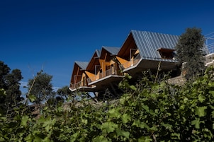 Una casa moderna con varios niveles y balcones, rodeada de vegetación.