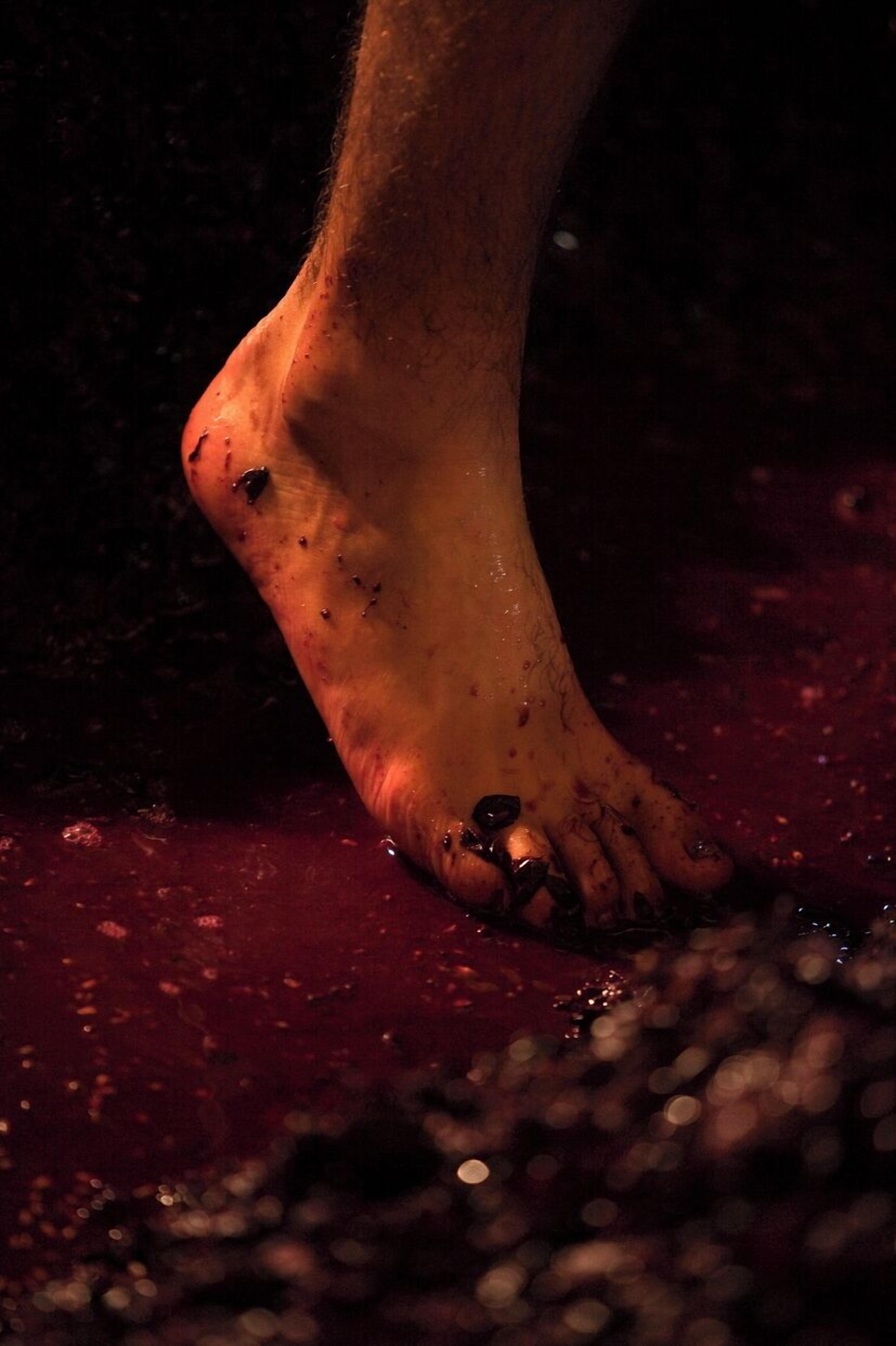 A close-up of a foot with visible dirt and a dark surface beneath it.