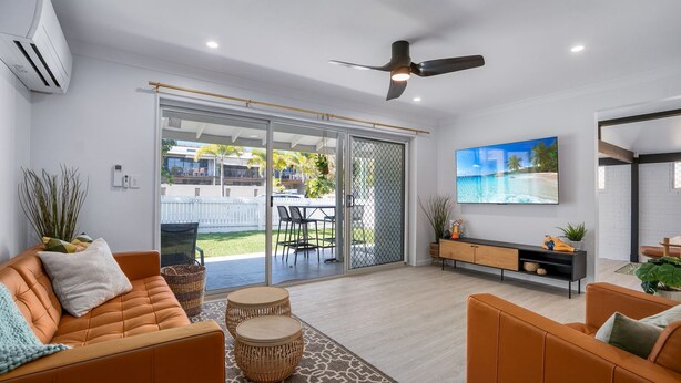 A modern living room with a sofa, a TV, and a ceiling fan.