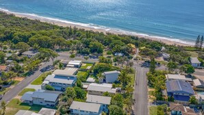 An aerial view of a coastal residential area with houses, roads, and a beach.