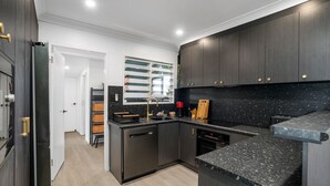 A modern kitchen with dark wood cabinets, a black granite countertop, and built-in appliances.