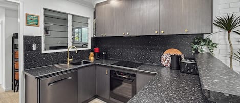 Una cocina moderna con armarios oscuros, encimera de granito y electrodomésticos de acero inoxidable.