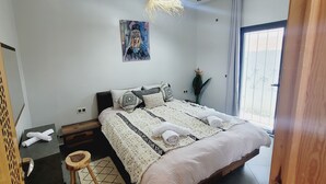 Una camera da letto con un letto, un comodino, una sedia, un quadro e una finestra con vista.