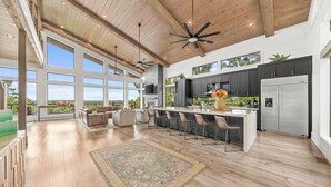 A spacious kitchen with a large island, dark cabinets, and a stainless steel refrigerator.