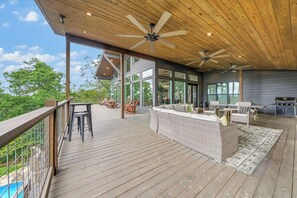 Una veranda coperta con mobili da esterno, ventilatori a soffitto e vista sul paesaggio.