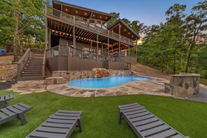 A two-story building with a pool, outdoor seating, and a stone deck. - Luxury Mountaintop Cabin • Pool w/ Rock Waterfall • Epic Views (Broken Bow)