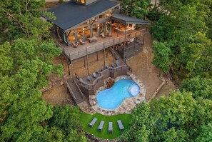 A two-story house with a large deck, a swimming pool, and a well-maintained lawn. - Luxury Mountaintop Cabin • Pool w/ Rock Waterfall • Epic Views (Broken Bow)