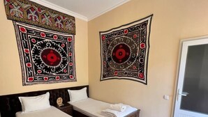 Une chambre d’hôtel avec deux lits simples, une grande fenêtre et deux tapisseries murales.