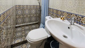 Une salle de bain avec douche, toilettes et lavabo.