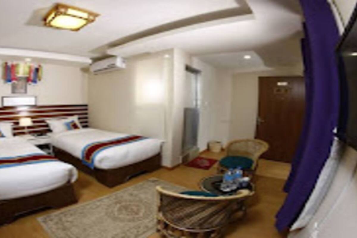 A hotel room with two beds, a small seating area, and a television.