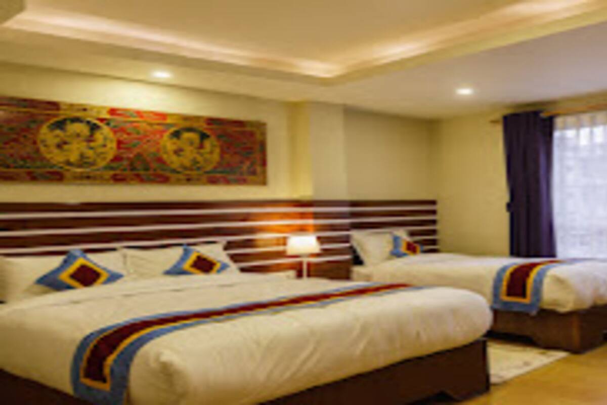 A hotel room with two beds, a large painting on the wall, and a window with curtains.