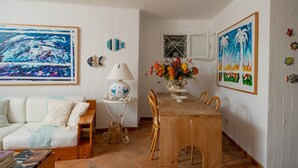 Een eethoek met een houten tafel en stoelen, een witte bank, een lamp en een bloevas.