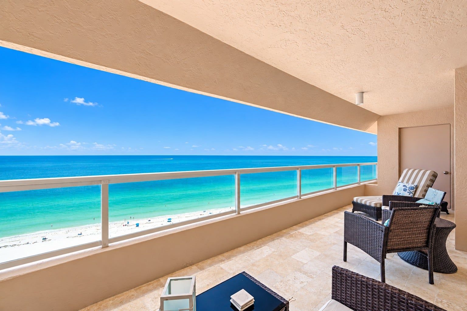 A balcony with a view of the beach and ocean.