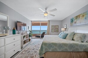 A bedroom with a bed, a TV, a ceiling fan, a view of the ocean, and a balcony. - 🩱CBC 1-15E – Private balcony, beachfront, pool, gym & pickleball! (Clearwater)