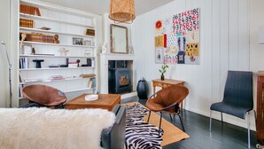 Una sala de estar con chimenea, estanterías, un cuadro abstracto de gran tamaño y muebles modernos.