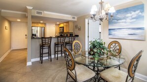 A dining area with a glass table, chairs, and a chandelier. - B.E.A.C.H.  Best Escape Anyone Could Have--  Let's Go!!  2 Bedroom / 2 Bath!! (Biloxi)