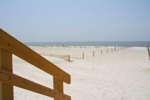 Ein Strand mit einer Holzstege, der zum Meer führt.