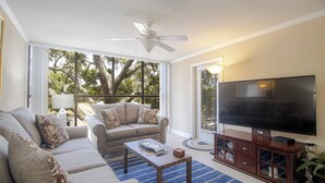 A living room with a sofa, a coffee table, a TV on a wooden stand, and a ceiling fan. - B.E.A.C.H.  Best Escape Anyone Could Have--  Let's Go!!  2 Bedroom / 2 Bath!! (Biloxi)