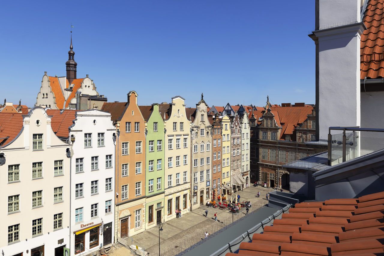 Eine Reihe bunter, historischer Gebäude vor strahlend blauem Himmel.