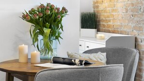Et moderne værelse med et træbord, to stearinlys, en vase med blomster og en grå stol.