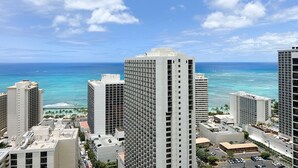 A high-rise hotel with multiple floors, a rooftop pool, and a view of the ocean. - Gorgeous Waikiki Ocean View! Full Kitchen, Free Wi-Fi, Close to Beach! (Honolulu)