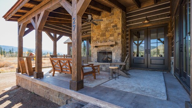 A wooden covered patio with a stone fireplace, outdoor seating, and a view of the mountains. - New Luxury home in Cascade Village - 2 miles to Purgatory - AC - Hot Tub/Pool (Durango)