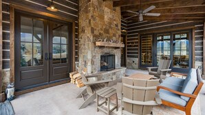 A log cabin interior with a stone fireplace, wooden furniture, and a ceiling fan. - New Luxury home in Cascade Village - 2 miles to Purgatory - AC - Hot Tub/Pool (Durango)
