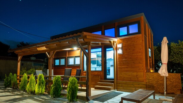 A modern wooden house with a covered patio, outdoor seating, and a stone-tiled patio. - Tiny Villa among the Olives. (hERAKLION)