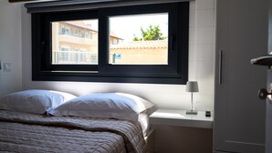 A bedroom with a bed, pillows, a window, a bedside table with a lamp, and a door. - Tiny Villa among the Olives. (hERAKLION)