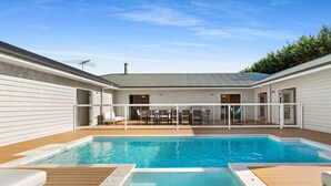 A swimming pool with a wooden deck, lounge chairs, and a covered patio area with tables and chairs. - Ultimate family retreat, on the Portsea / Sorrento border, (sleeps 15/16) (Portsea)