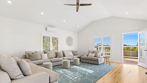 A spacious living room with a large sectional sofa, ottomans, and a geometric rug. - Ultimate family retreat, on the Portsea / Sorrento border, (sleeps 15/16) (Portsea)