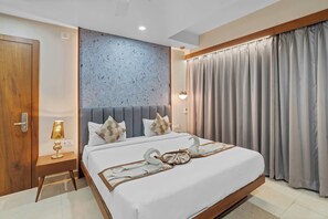 A modern hotel room with a large bed, a headboard with a textured wall, a bedside table with a lamp, and a curtain on the window. - HOTEL OCEAN BREEZE (Bhopal)