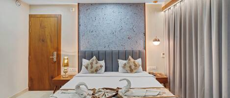 A hotel room with a large bed, wooden door, and a headboard with a textured wall behind it.