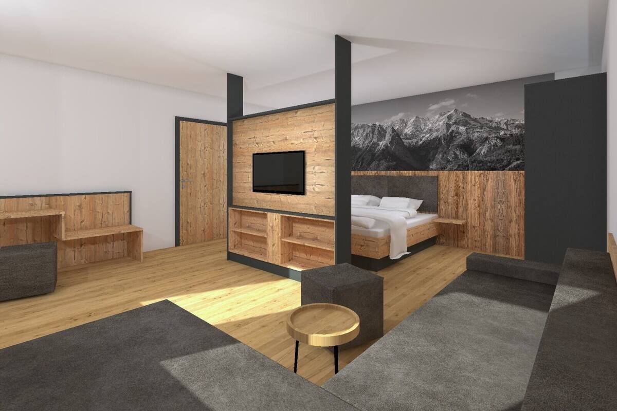 A modern hotel room with a wooden accent wall, a flat-screen TV, a bed with white bedding, a sofa, and a small round table.