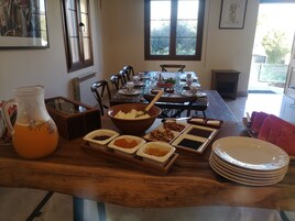 Una mesa de comedor preparada con diferentes platos y una jarra de jugo de naranja.