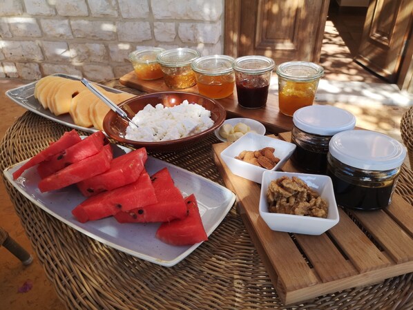 A table with various food items including watermelon, nuts, and jars of preserves.