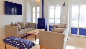 Ein Wohnzimmer mit einer Couch, einem Sessel, einem Hocker und einem Kamin.