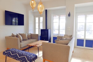 Una sala de estar con sofá, sillón, reposapiés y chimenea.