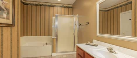 A bathroom with a bathtub, a shower enclosure, a sink, and a large mirror.