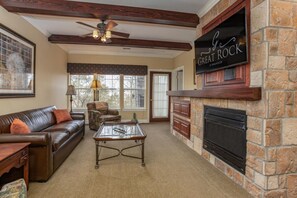 A cozy living room with a stone fireplace, leather sofa, and a coffee table.