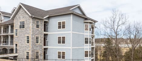 A multi-story residential building with a stone facade and blue siding.