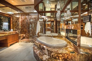 Ein luxuriöses Badezimmer mit einem großzügigen Marmorwaschtisch, einer freistehenden Badewanne und einem großen Spiegel, der den Raum widerspiegelt.