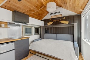 Ein kleiner Raum mit Bett, Küchenzeile und einem Schild mit der Aufschrift 'PROVINGETOWN'.